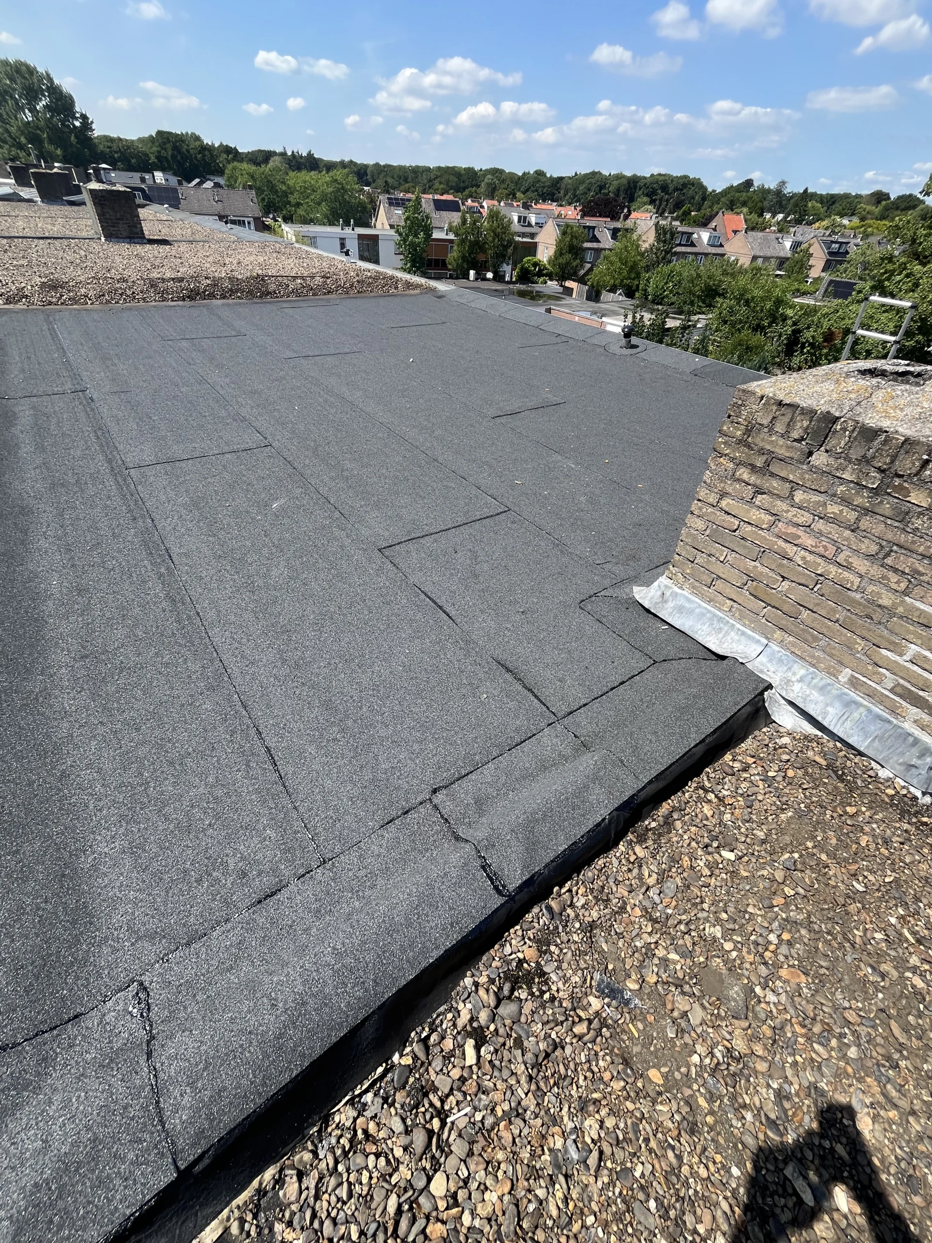 Plat dak voorzien van nieuwe bitumen dakbedekking en grind door De Dakdekker Den Haag.